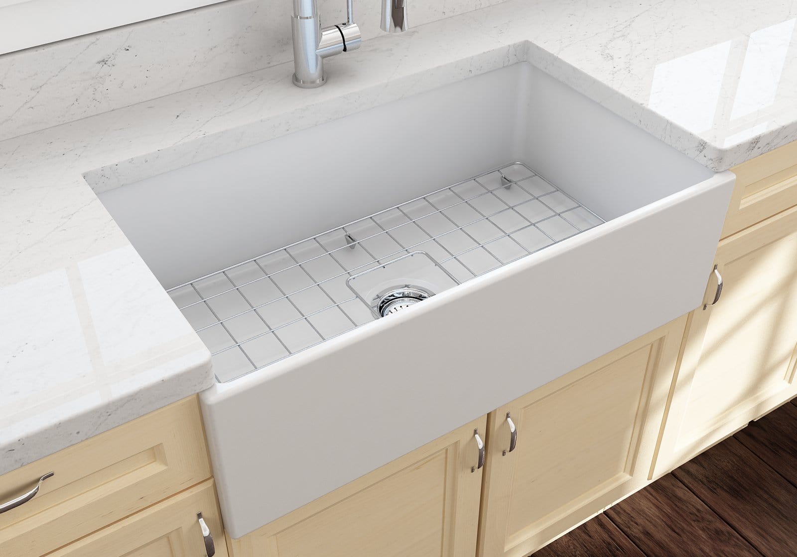 White fireclay apron-front farmhouse kitchen sink installed in a bright kitchen with marble countertops