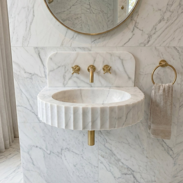 Marble sink with gold fixtures in a bathroom setting. Carrara White Marble Wall-mount Bathroom Sink Fluted Front (W)16" (L)24" (H)6"