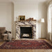 Living room with marble fireplace, armchair, and patterned rug.