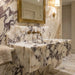 Marble bathroom vanity with gold fixtures and mirror