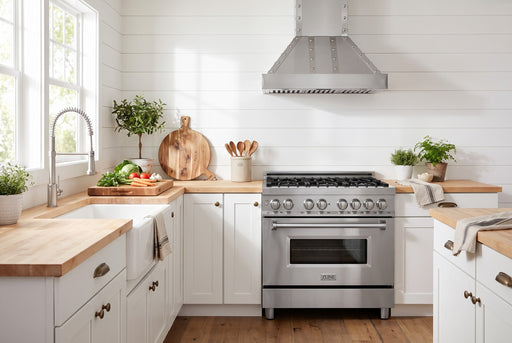 ZLINE 36-inch stainless kitchen set staged together in a farmhouse kitchen: RA36 gas range, 655-4SSSS-36 wall hood mounted above, and Apollo brushed-nickel faucet at the sink